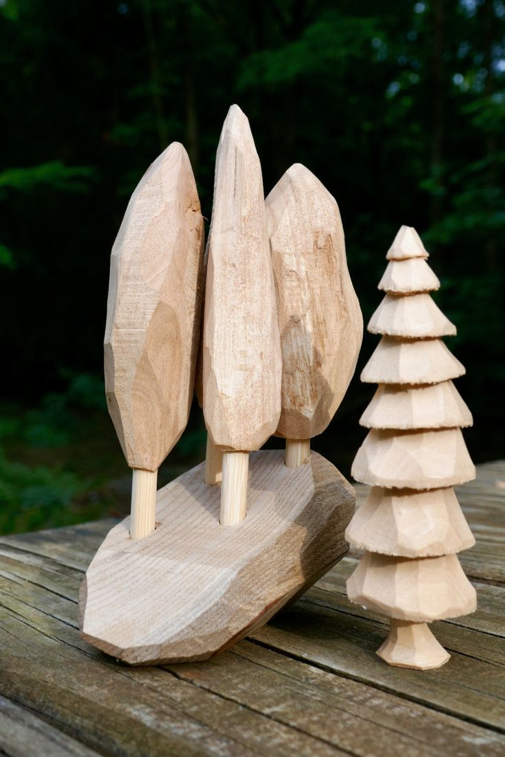 three wooden trees sitting on top of a wooden table next to each other in front of a forest