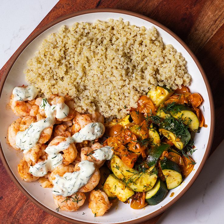 a white plate topped with rice and veggies on top of a wooden table