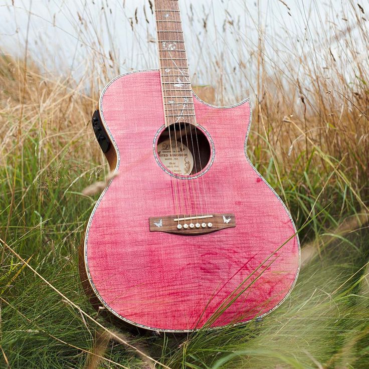 a pink guitar is sitting in the grass