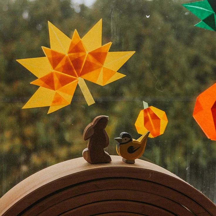 some paper decorations are hanging on the window sill in front of an umbrella and tree