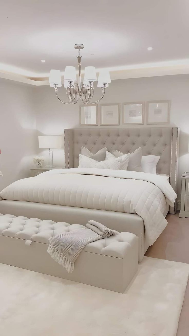 a large white bed sitting in a bedroom next to a chandelier