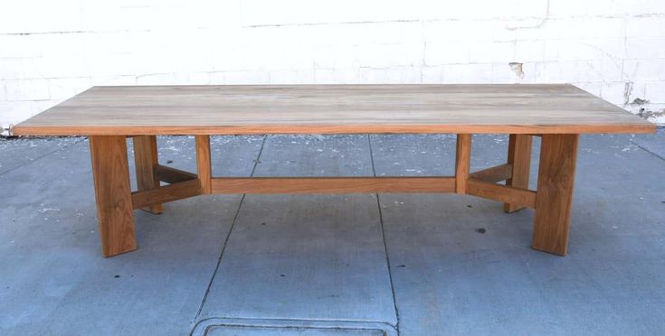 a wooden table sitting on top of a cement floor next to a white brick wall