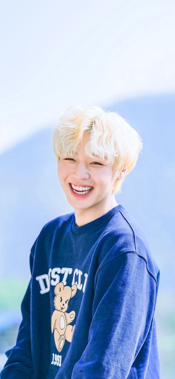 a young boy with blonde hair smiles at the camera