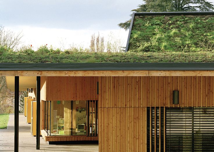 a wooden building with a green roof and windows