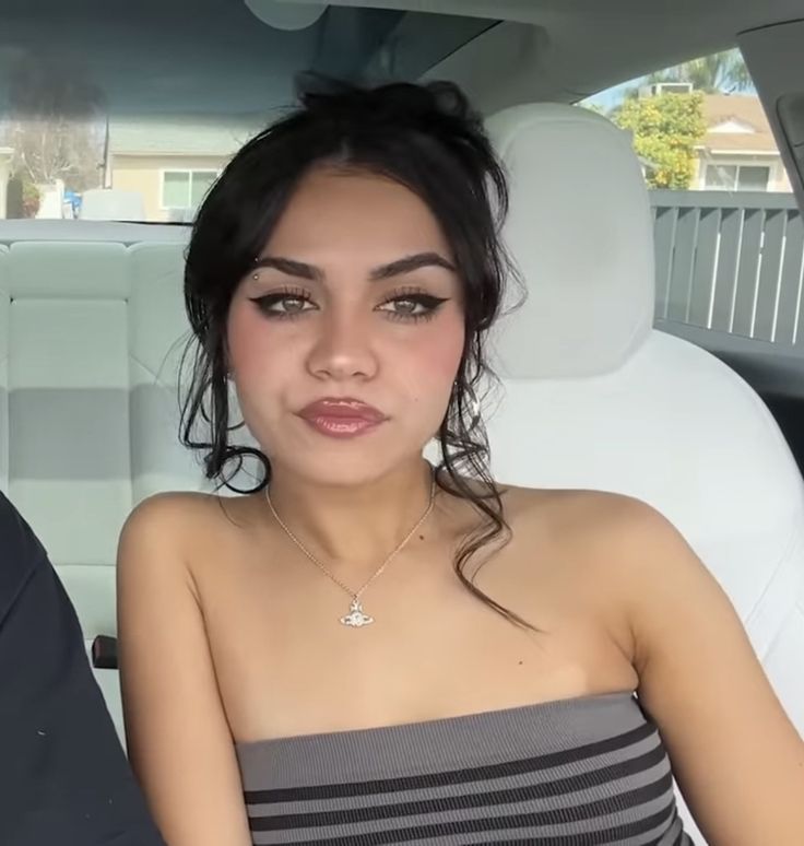 a woman sitting in the back seat of a car with her hand on her hip