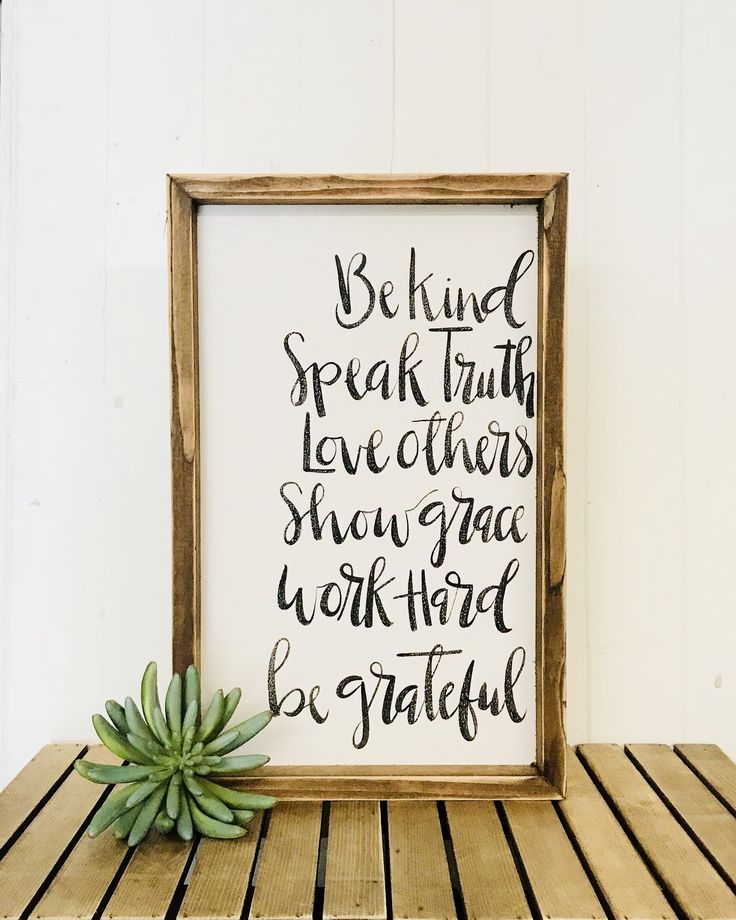 a wooden table topped with a framed sign and a succulent plant next to it