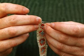 the hands of an older woman are knitting together