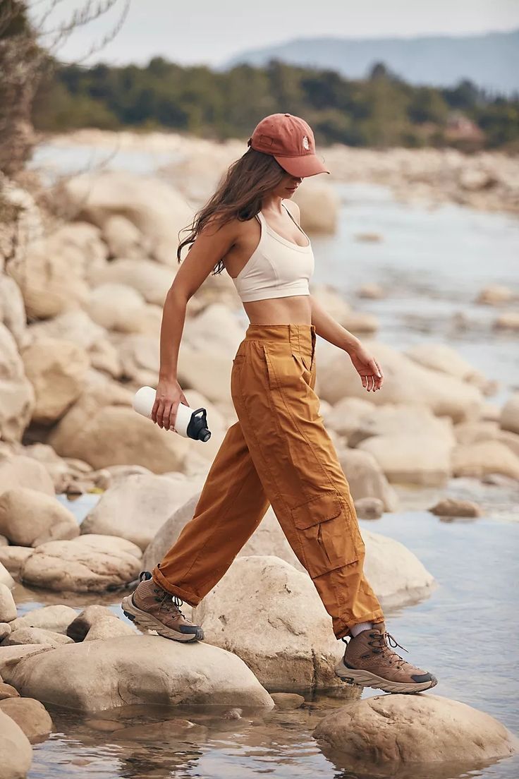 a woman is walking on rocks near the water