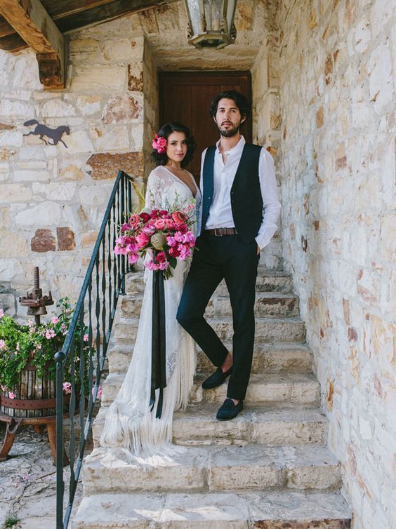 a man and woman standing on the steps of a building with flowers in their hair