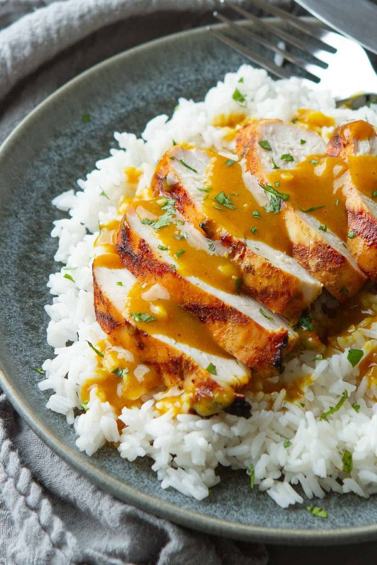 a plate with rice, chicken and gravy on it next to a fork