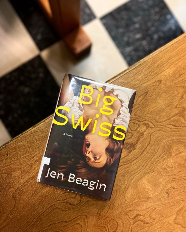 a book sitting on top of a wooden table next to a black and white checkered floor