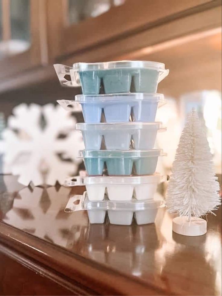 a stack of plastic cups sitting on top of a wooden table next to a christmas tree