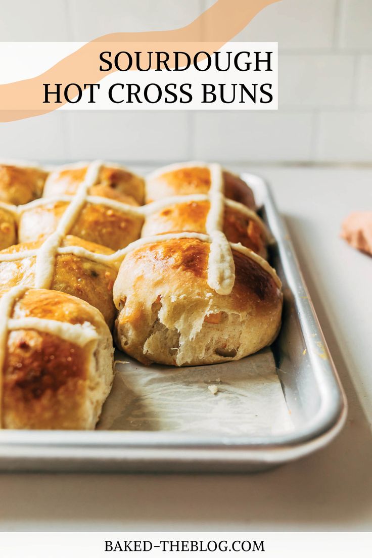 hot cross buns on a baking sheet with text overlay that reads, sourdough hot cross buns