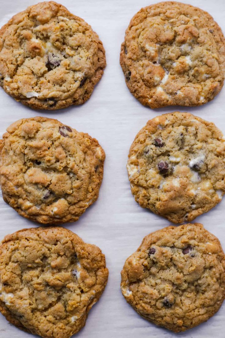 six chocolate chip cookies sitting on top of a white paper