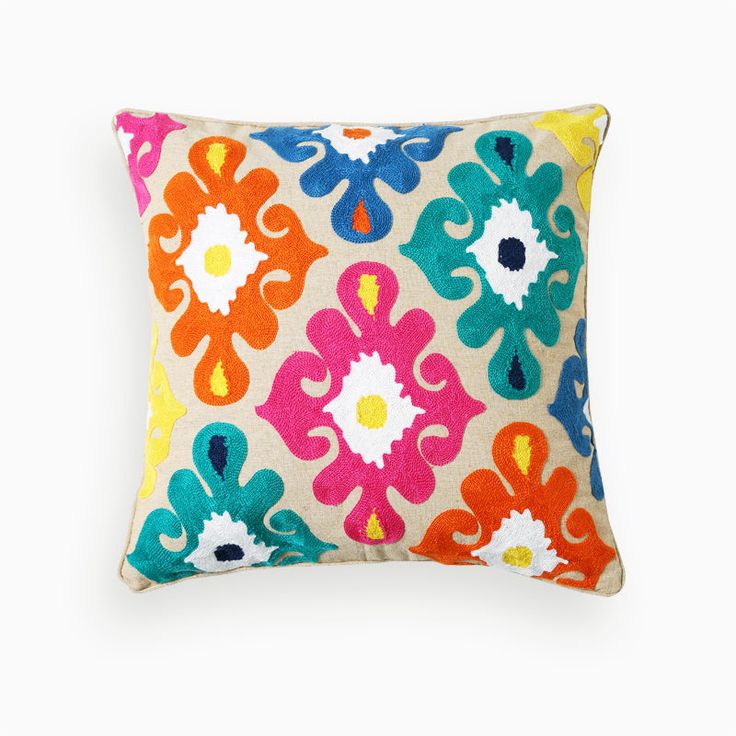 a multicolored pillow with an ornate design on the front and back, sitting against a white background