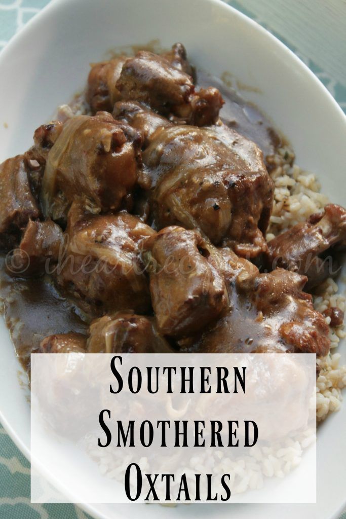 a white bowl filled with meat and rice covered in gravy on top of a table