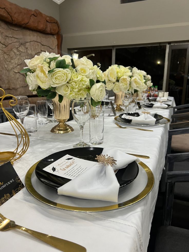 the table is set with white and gold plates, silverware, and napkins