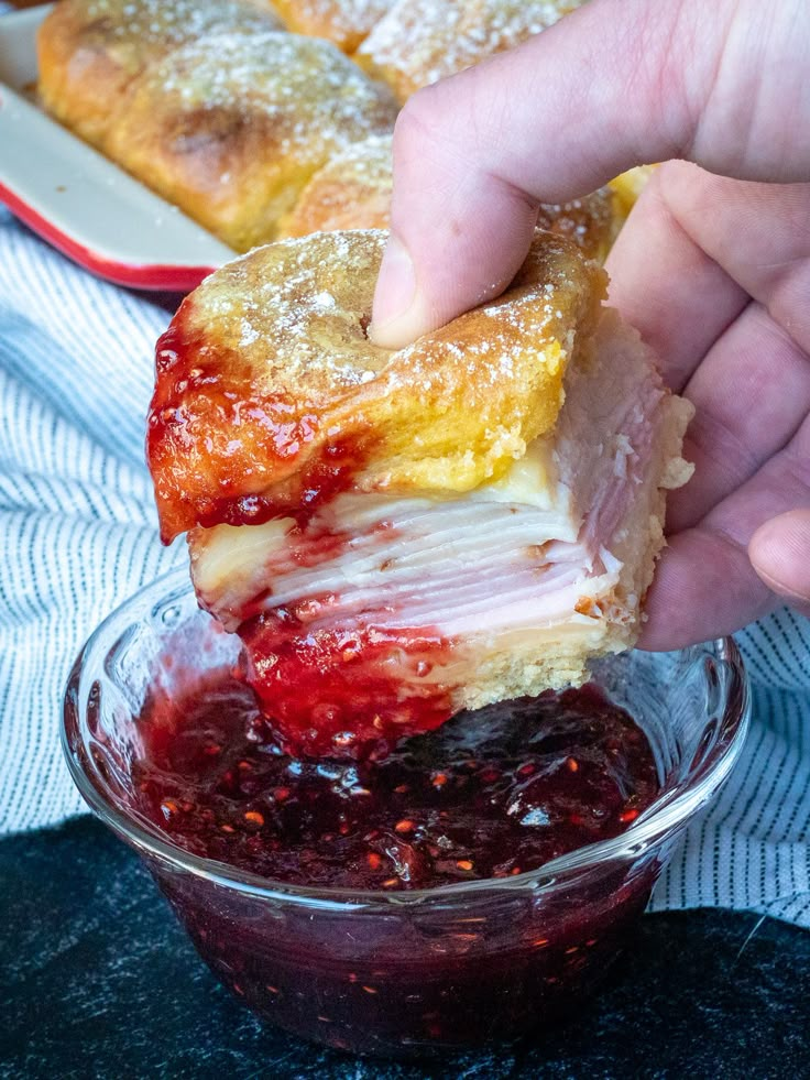 a person dipping jelly into a dessert in a glass bowl on top of a table