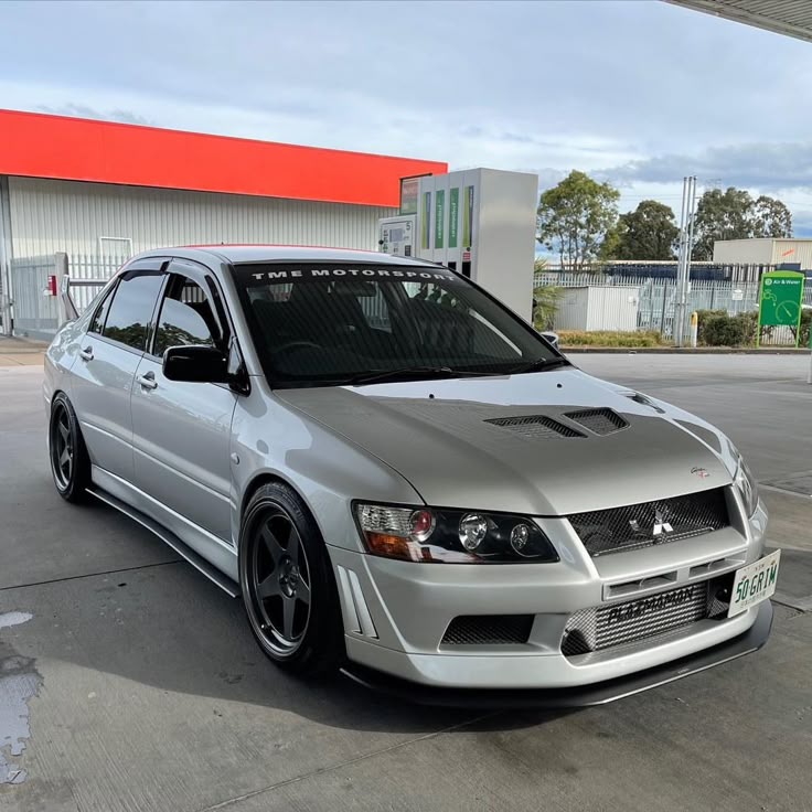 a silver car parked in front of a gas station