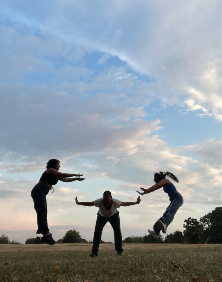 three people are jumping in the air with their hands out and one person is wearing jeans