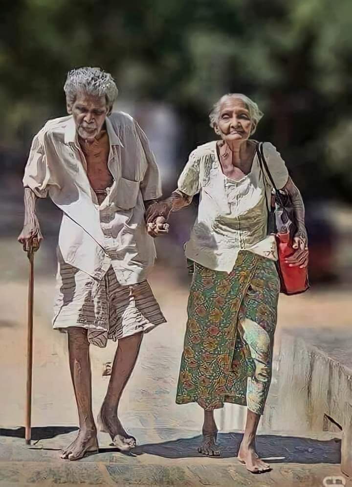 an old couple walking down the street with canes and bags on their shoulders, holding hands