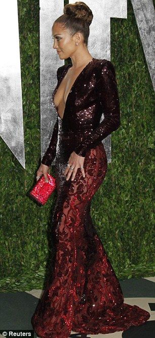 a woman in a red and black gown at the vanity awards party, with her hand on her hip