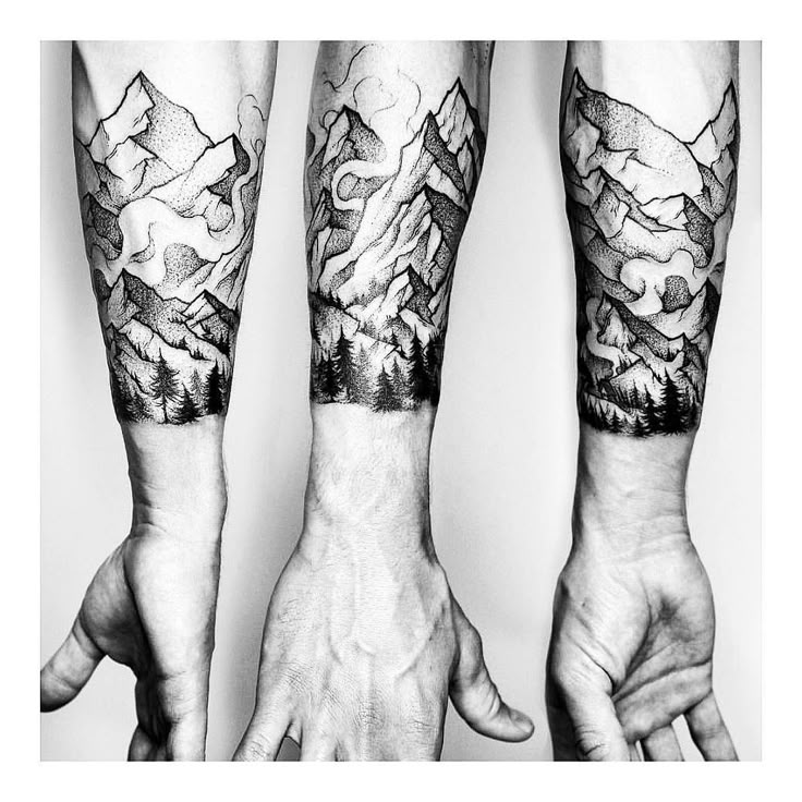 two men's arms with mountains and clouds tattooed on their arm, both holding hands