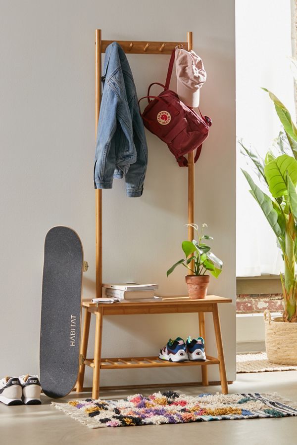 a skateboard and coat rack in the corner of a room with potted plants