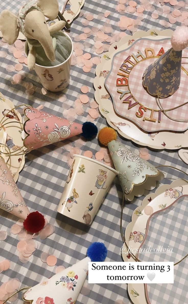 a table topped with plates and cups filled with confetti next to an elephant