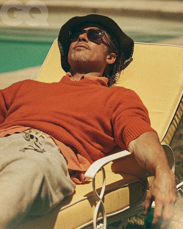 a man laying on top of a yellow lawn chair next to a swimming pool wearing sunglasses and a hat