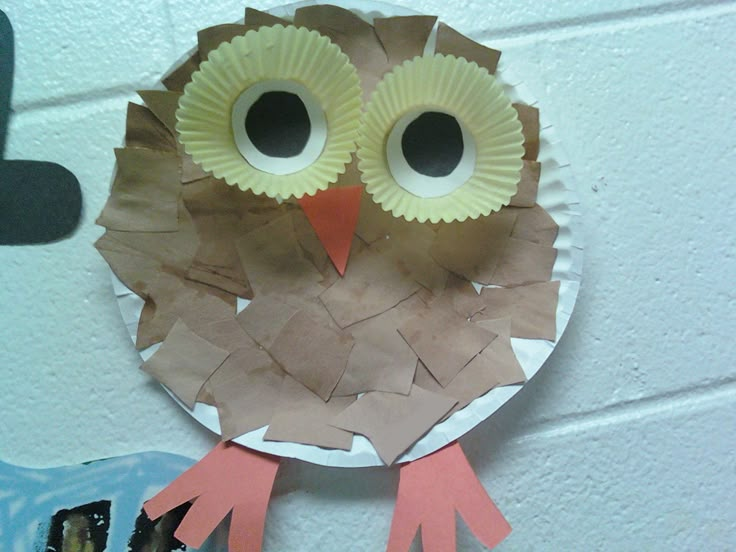 an owl made out of paper sitting on top of a wall