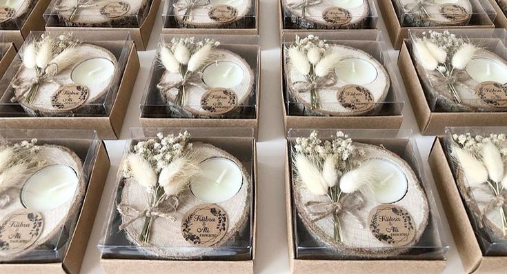 twelve boxed candles in boxes with dried flowers and feathers on the top one candle is white