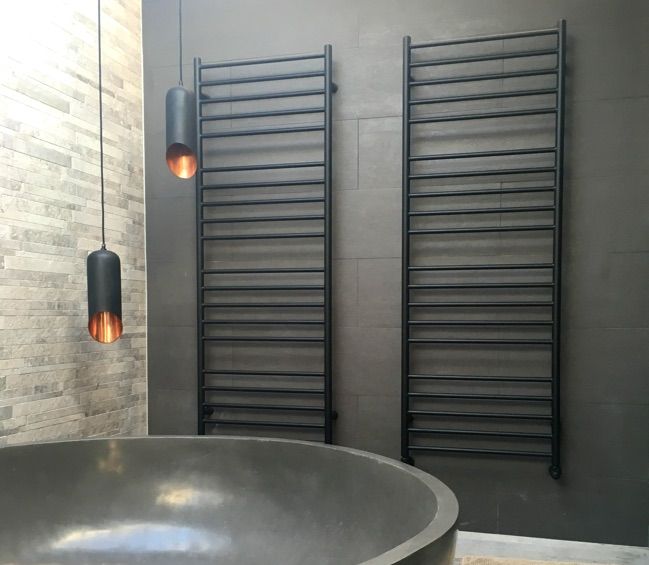 a bathroom with a round bathtub next to a wall mounted heater and two hanging lights