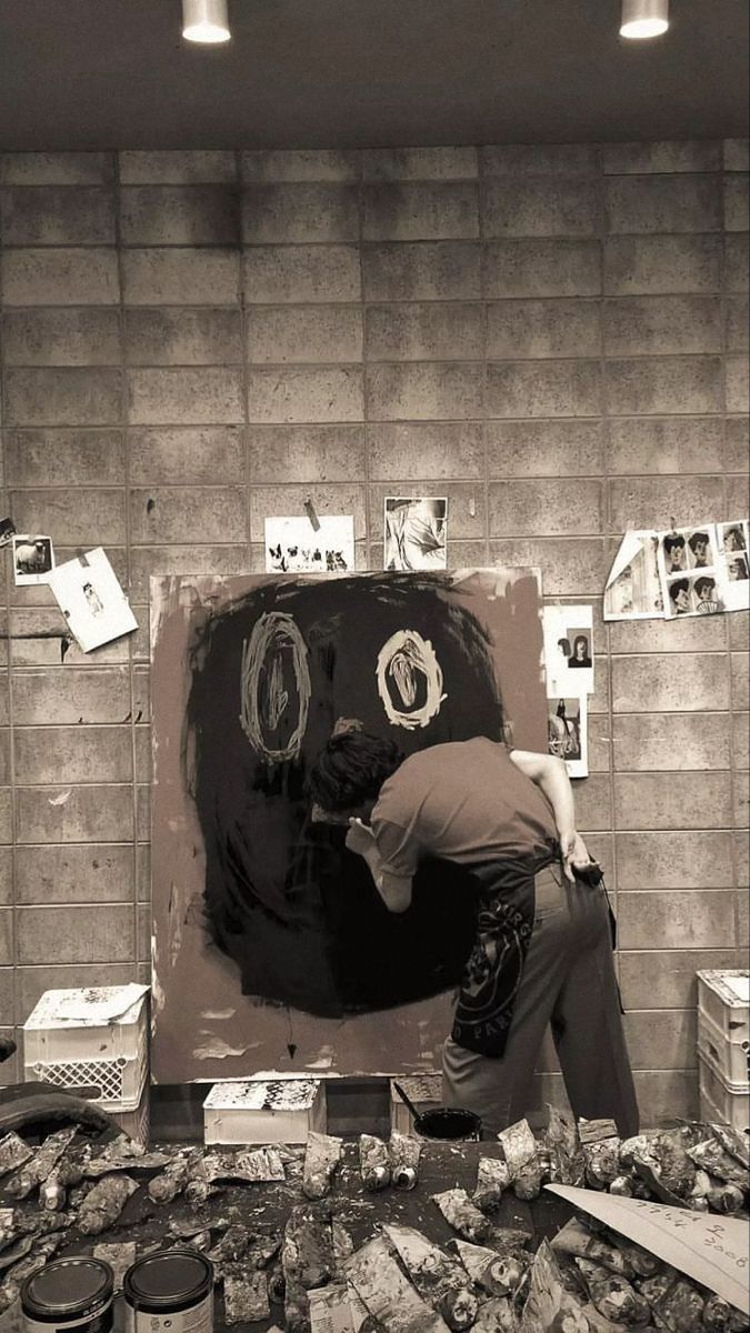 a man is painting on the wall with black paint