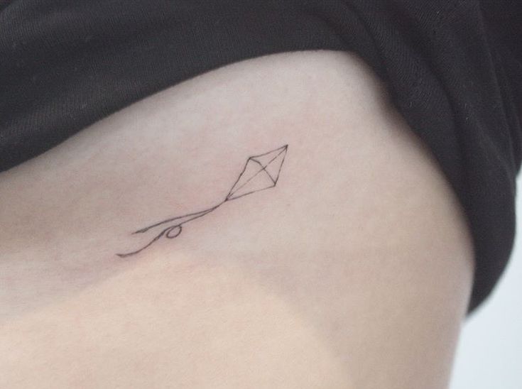 a small kite tattoo on the back of a woman's stomach, which is drawn in black ink