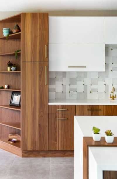 a kitchen with wooden cabinets and white counter tops, along with potted plants on shelves