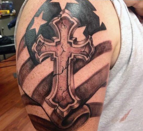 a cross with an american flag tattoo on his arm and shoulder is shown in this image