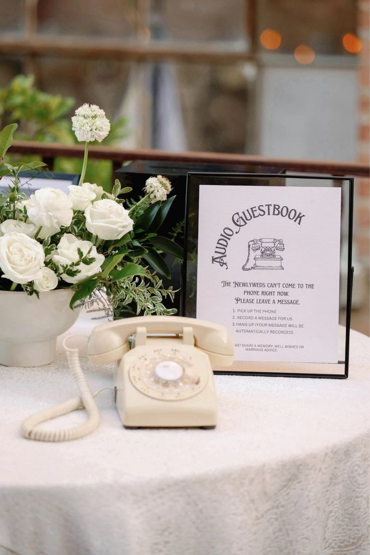 an old fashioned phone sitting on top of a table next to a vase with flowers