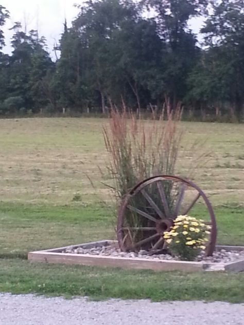 an old wheel is sitting in the middle of a field