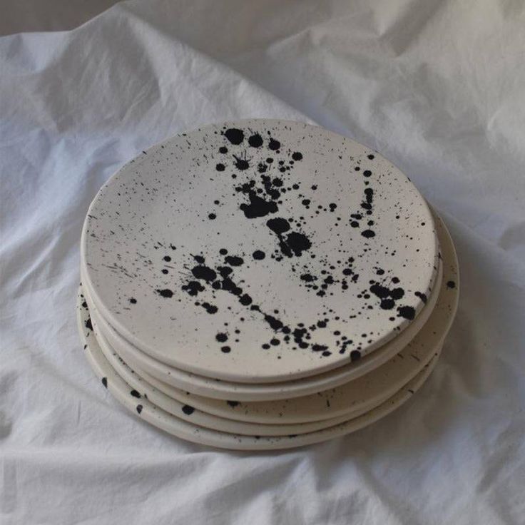 four white plates with black splatters on them