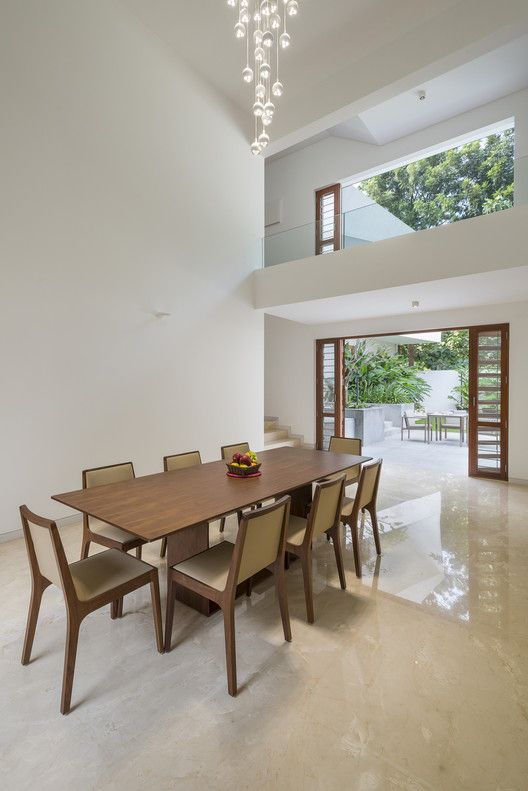 a dining room table with chairs and a bowl of fruit on it in front of an open floor plan