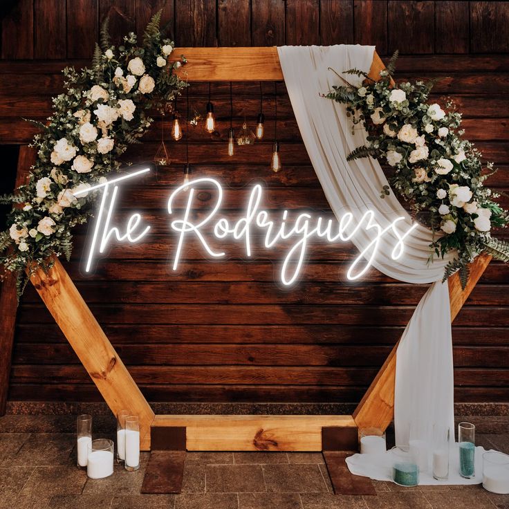 the wedding sign is lit up with flowers and greenery as well as candles in front of it