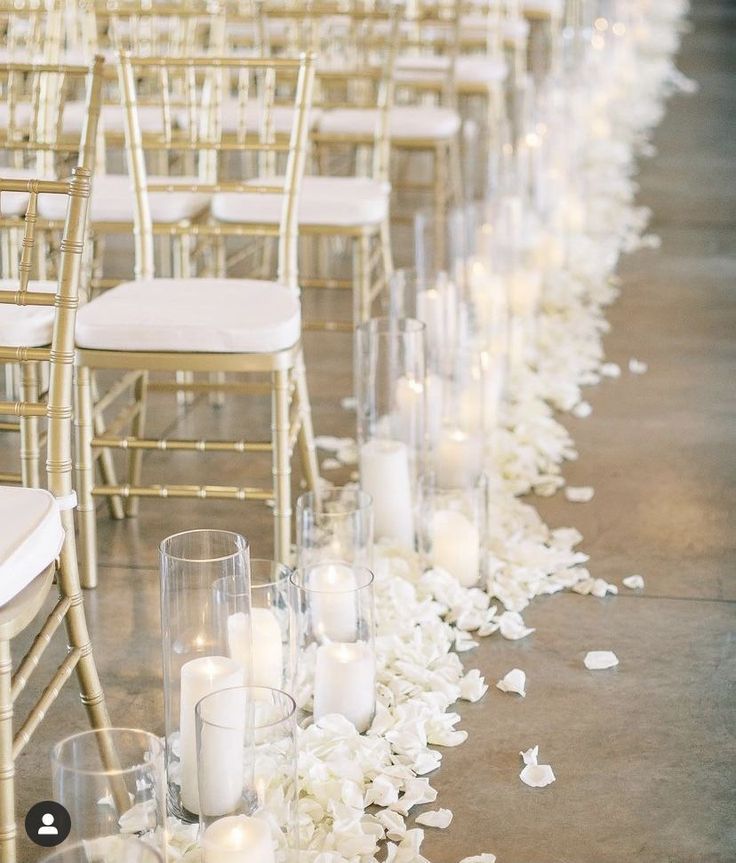 rows of chairs lined up with white flowers and candles on the floor in front of them