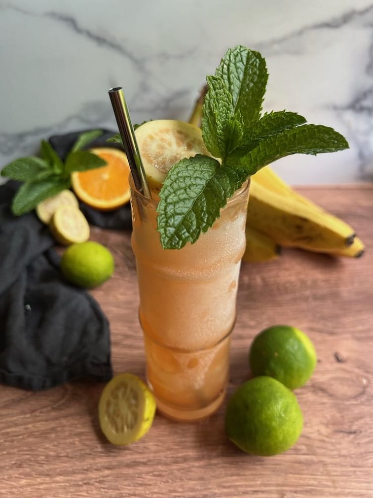 a glass filled with lemonade and mint on top of a wooden table