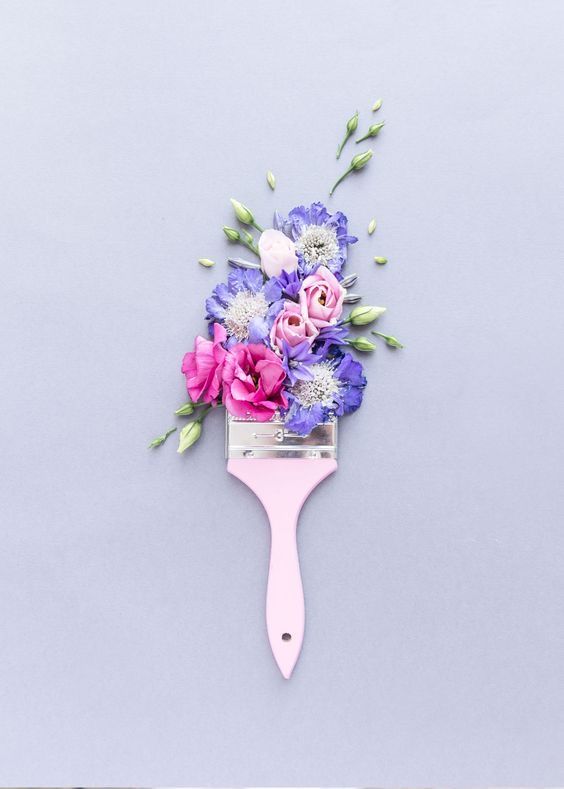 a hair brush with flowers on it sitting next to a gray wall and blue background