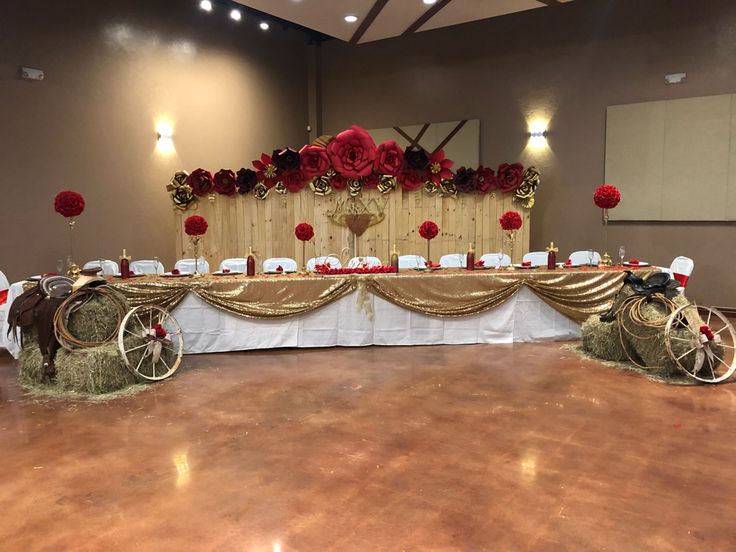 a decorated table with hay and red roses on the headboard is set up for a formal function