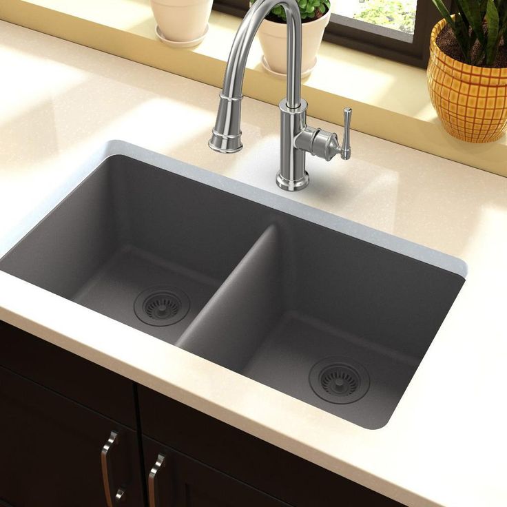 a kitchen sink with two faucets on the side and potted plants in the window sill