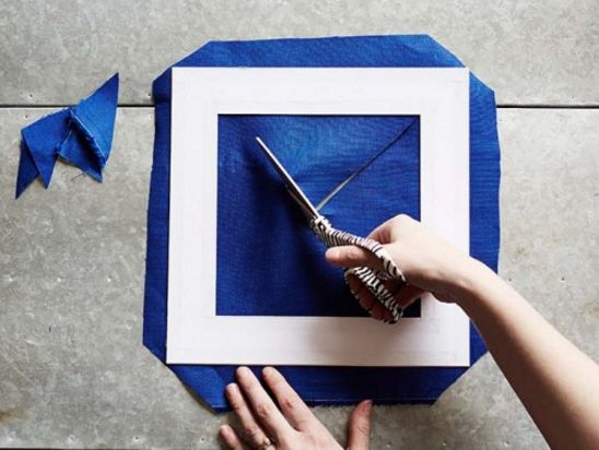 someone is cutting out a blue square with scissors