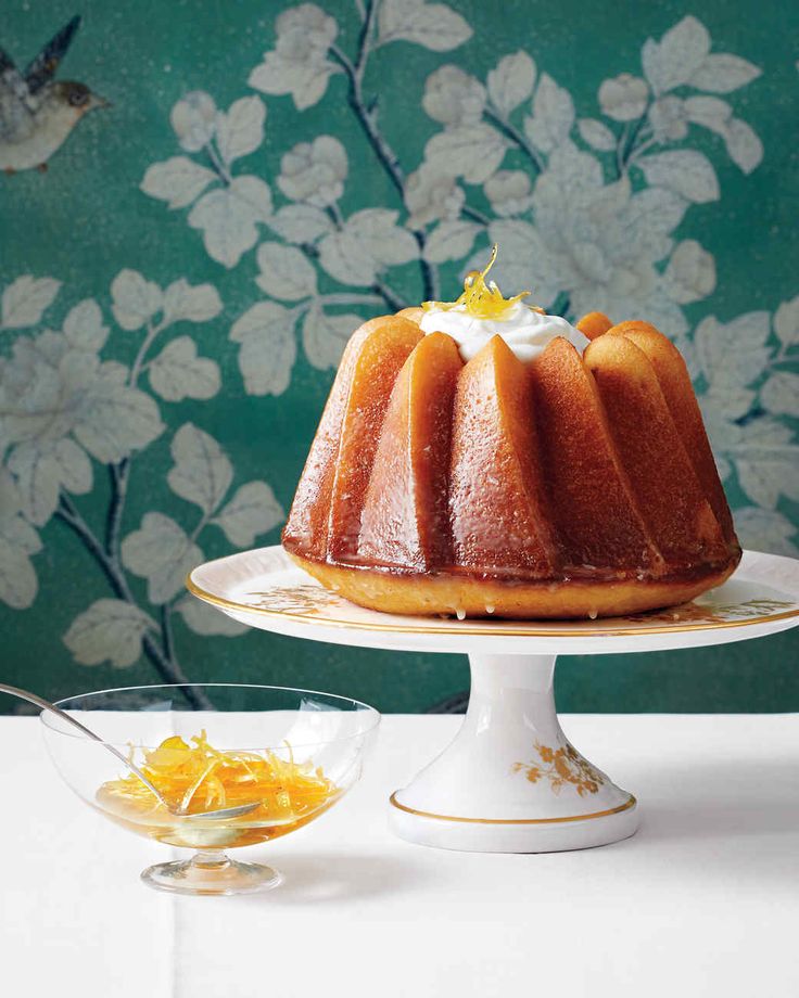 a bundt cake sitting on top of a white plate next to a bowl of fruit