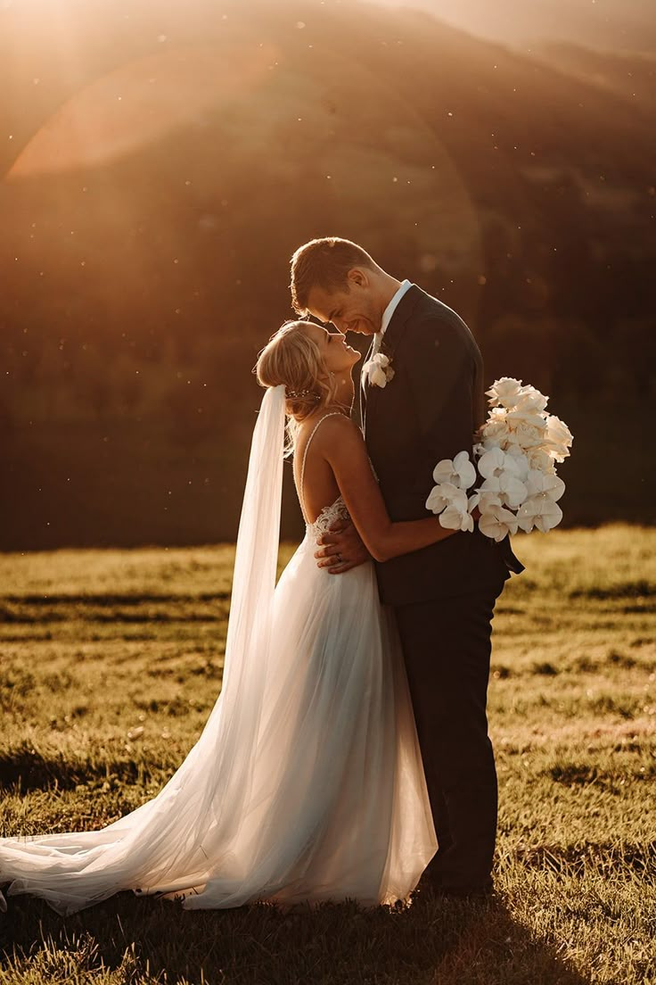 a bride and groom kissing in front of the sun